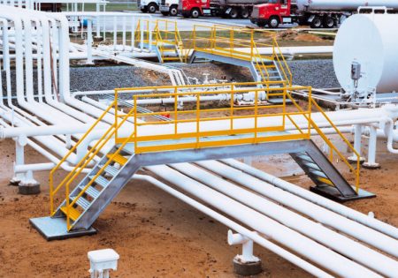 An OSHA Compliant Crossover traverses a series of pipes in an industrial setting.