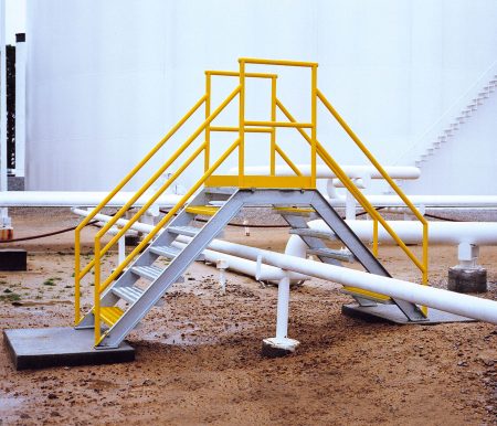 A crossover stairway over a pipeline in a refinery.