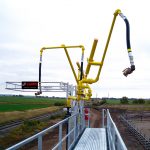 A top loading arm sits above a catwalk on a loading platform.