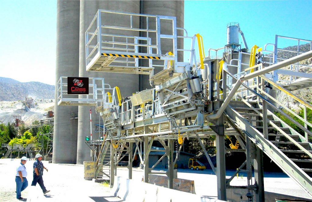 Two gangways are on a platform at with truck safety cages at a cement making facility.