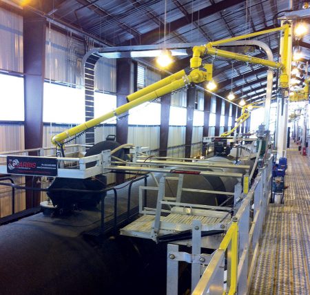 Two Carbis Solutions top loading arms are positioned above tanker railcars to load them.