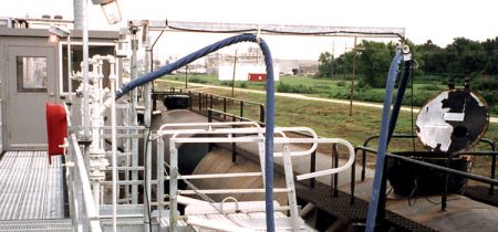 Hose handlers hold a hose over rail cars in a loading station.