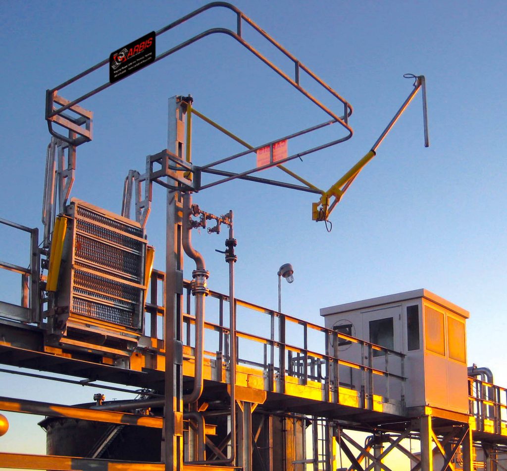 A top loading arm sits above a catwalk on a loading platform.