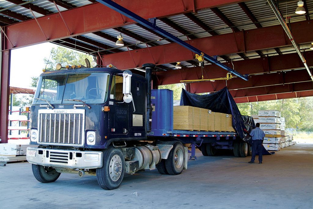A truck's load is being tarped with an overhead tarping solution.
