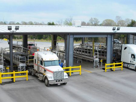 A flatbed tarping dock with several stalls and a loaded 18 wheeler being tarped.
