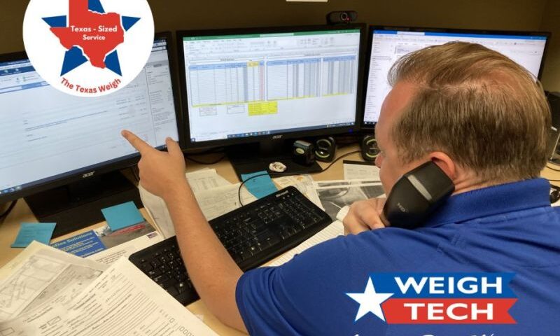 picture of a Weigh-Tech employee pointing at one of three computer screens while he is on the phone.